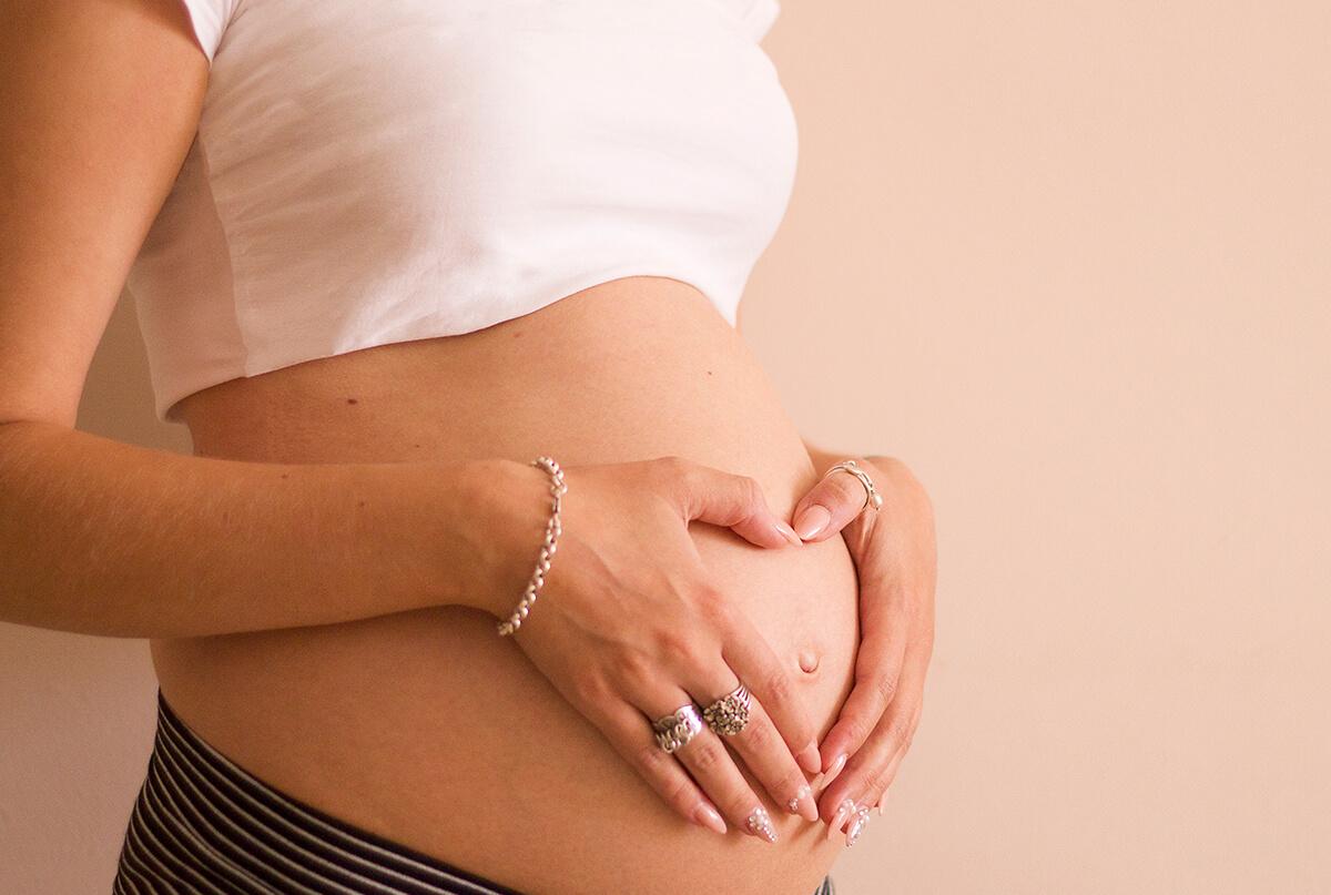 Gestante fazendo um coração com a mão na barriga