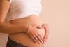 Gestante fazendo um coração com a mão na barriga